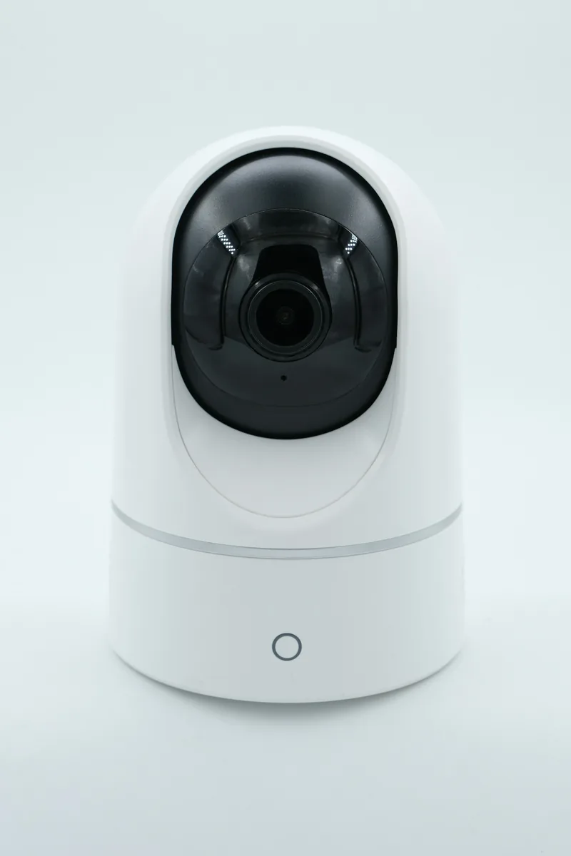 A small white indoor Wi-Fi camera on a white surface
