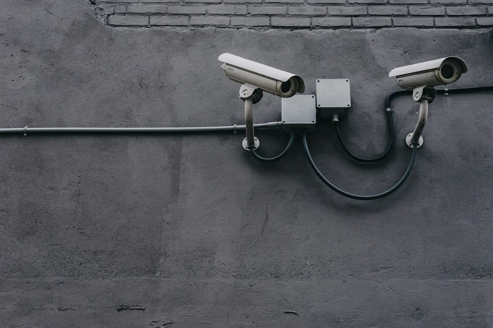 Two bullet surveillance cameras mounted on a concrete wall