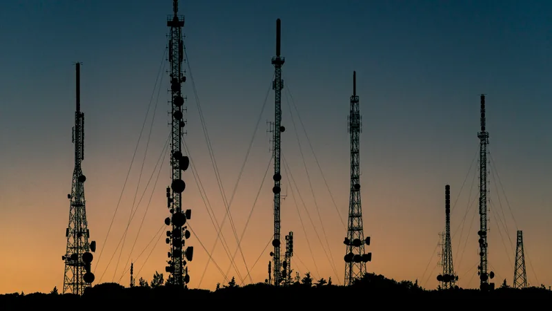 Radio and cellular towers silhouetted against a sunset