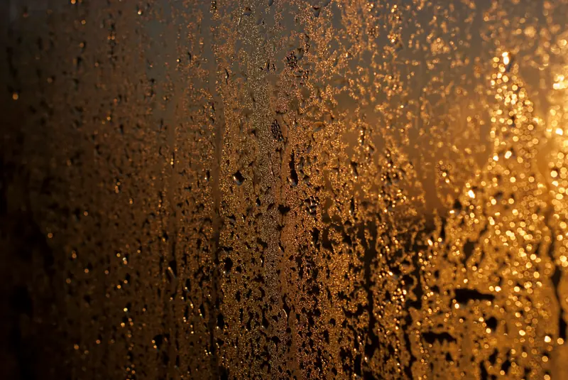 Condensation droplets on a window pane in warm light