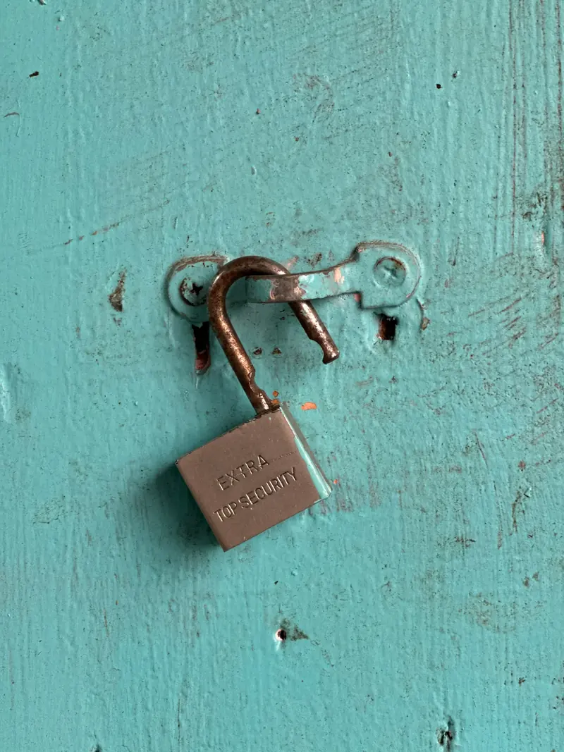 An unlocked padlock on a teal wooden surface